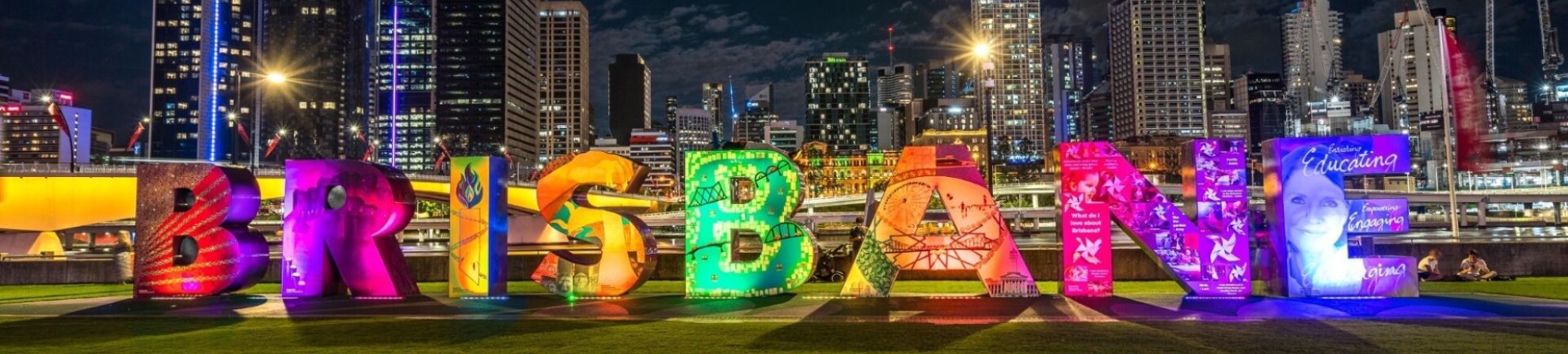 Large, illuminated Brisbane sign in Southbank in front of the city skyline. 